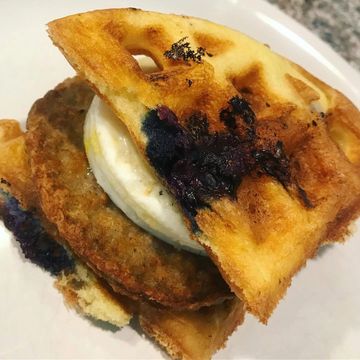 A burnt sandwich with sausage and egg inside.