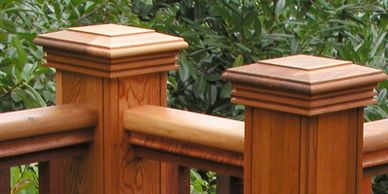 Wood post caps resting atop a wood deck railing