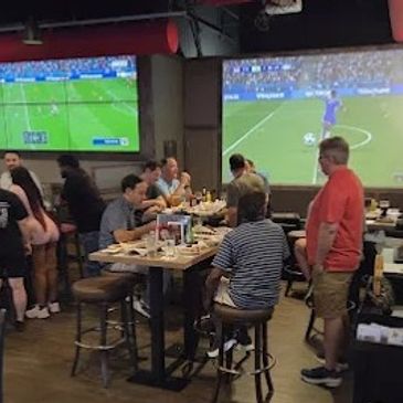 People watching soccer games at a sports bar with multiple screens.
