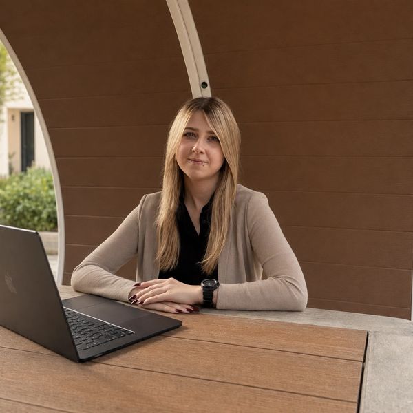 Woman sitting outside with a laptop on the table.
