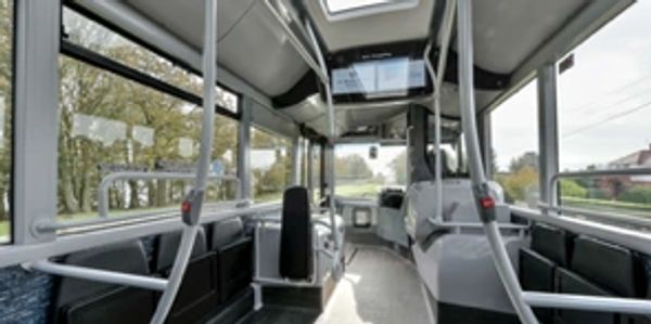 Empty modern city bus interior with large windows and bright lighting.