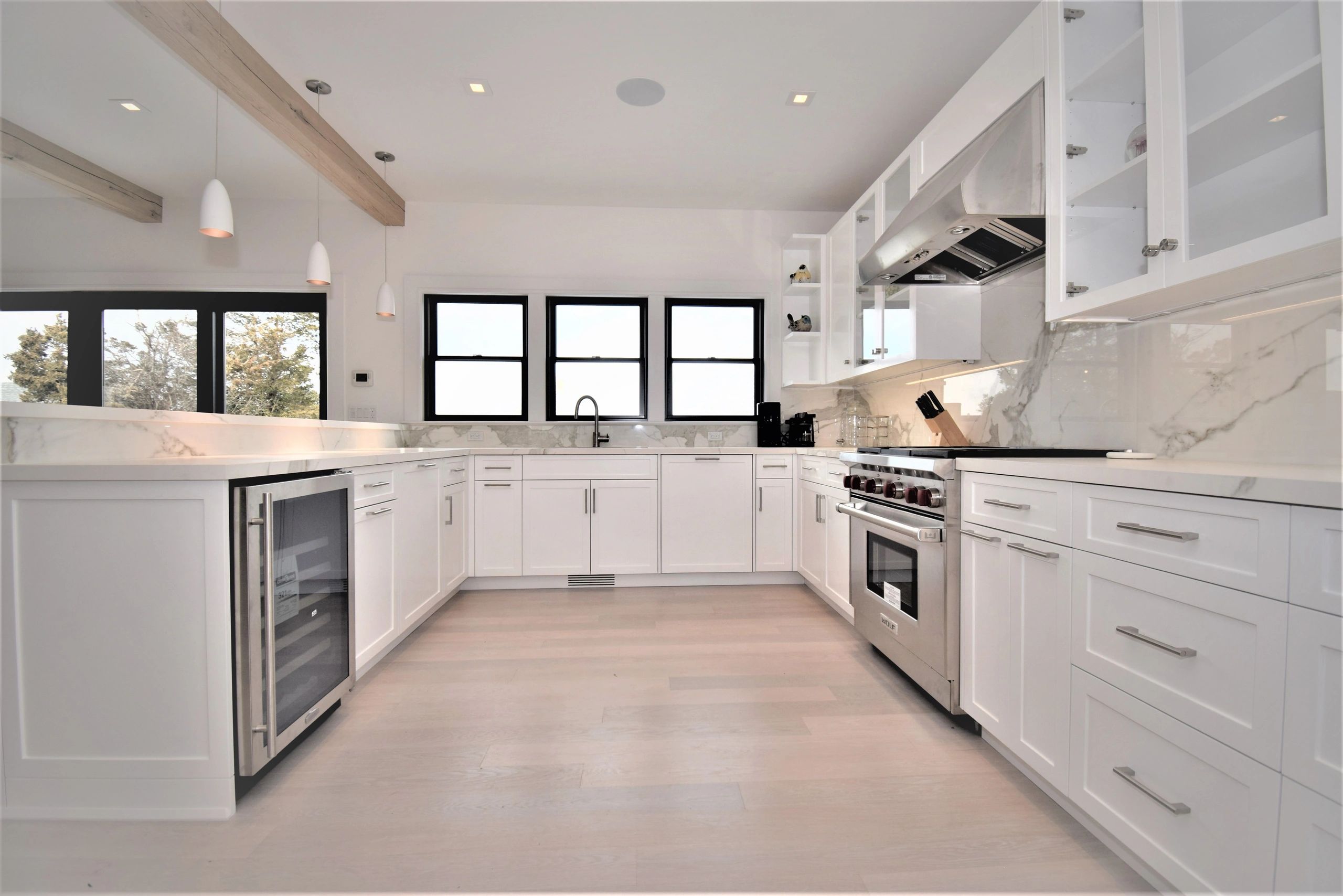 Bright modern kitchen with white cabinetry and stainless steel appliances.