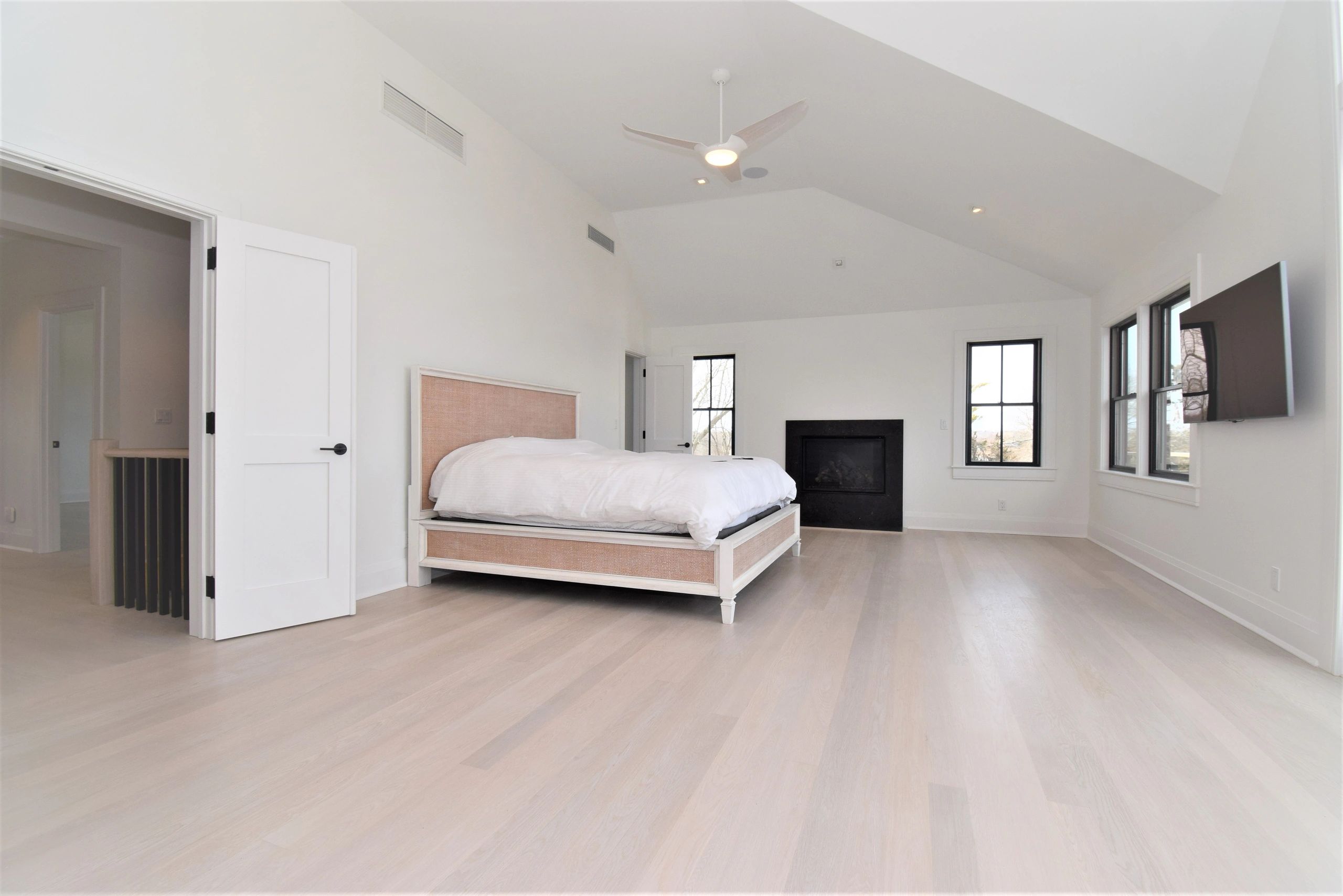 Minimalist bedroom with light wood floors and white walls.