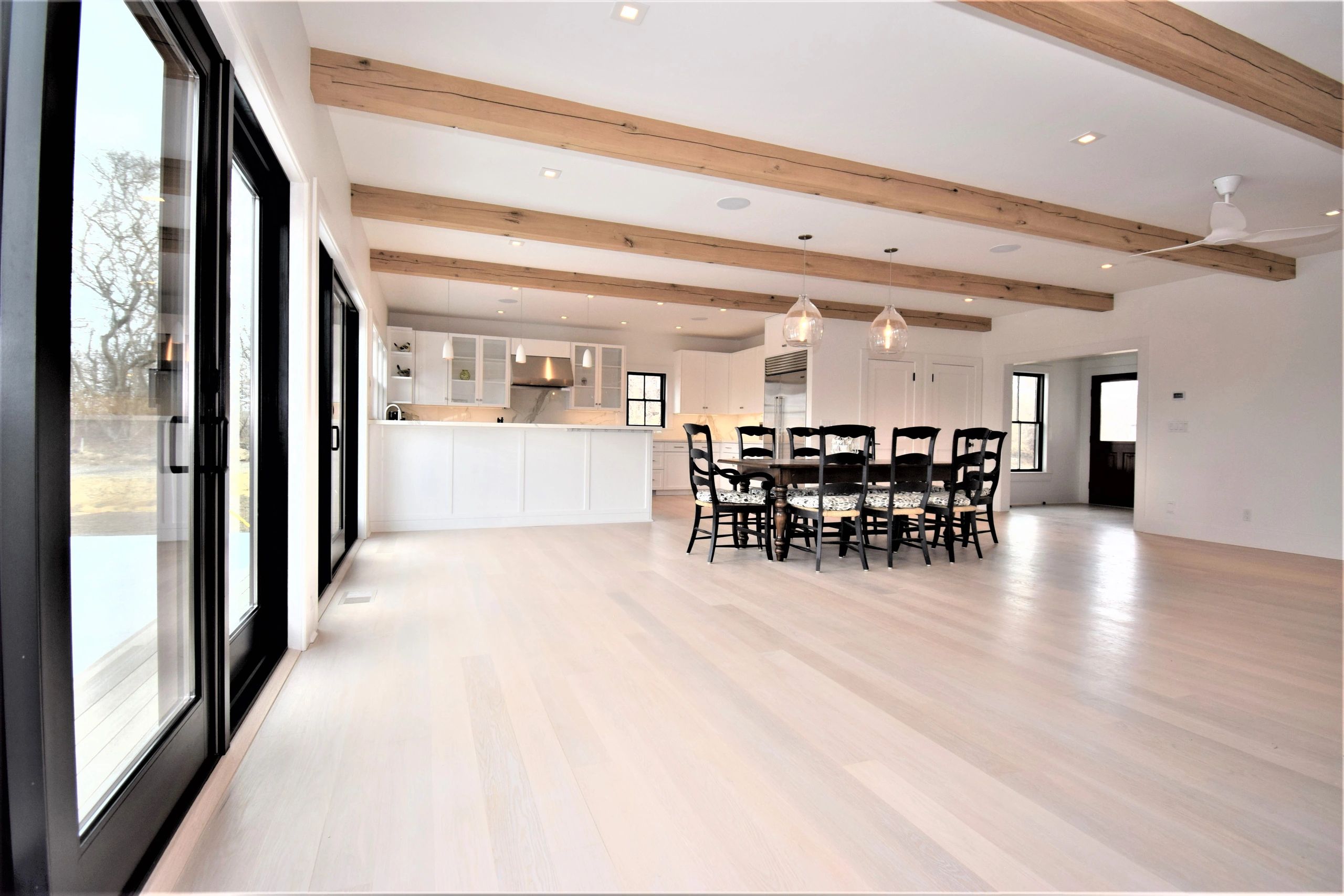 Bright modern kitchen and dining area with wooden ceiling beams.