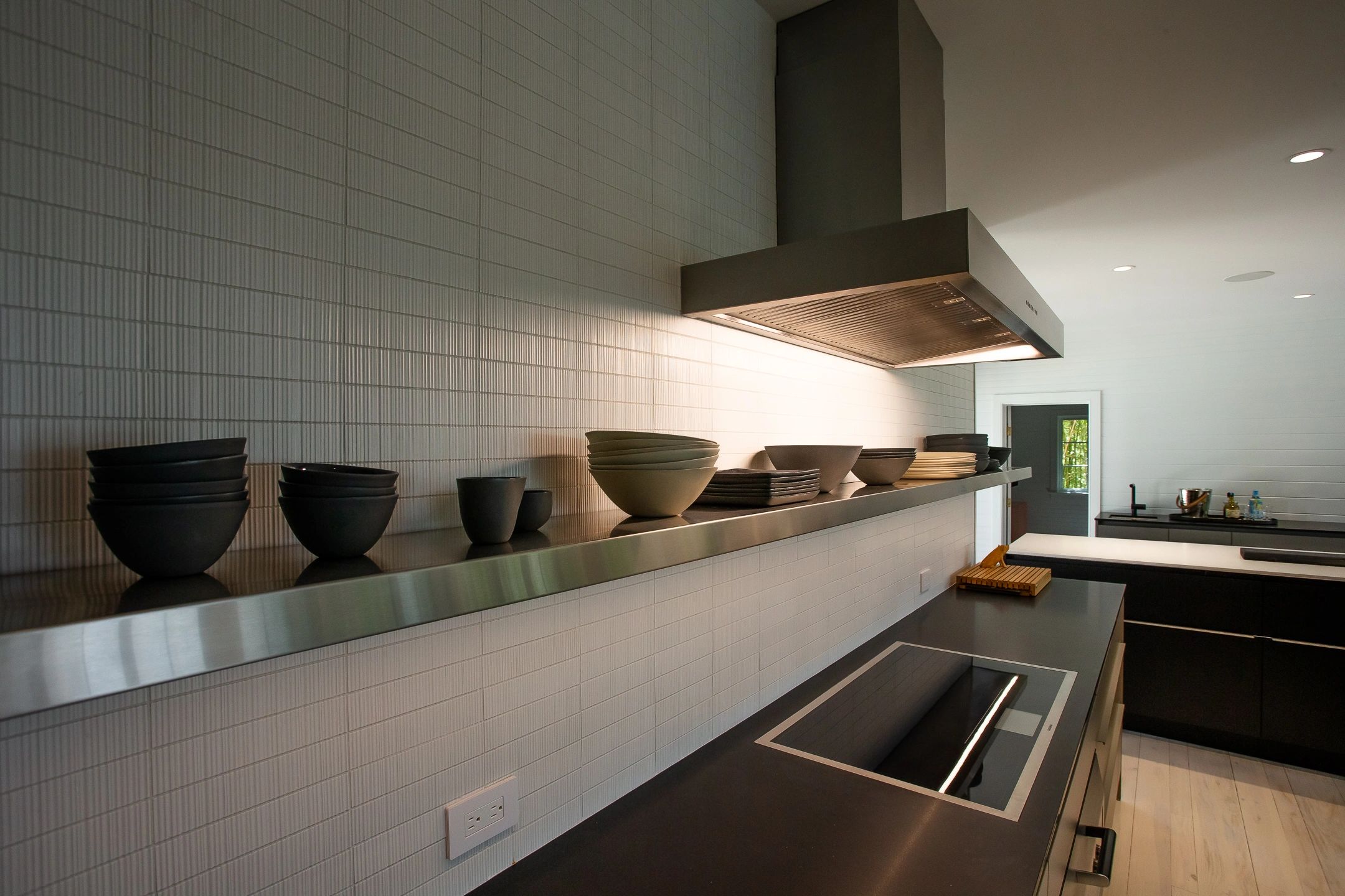 Modern kitchen with black bowls and stainless steel stove.