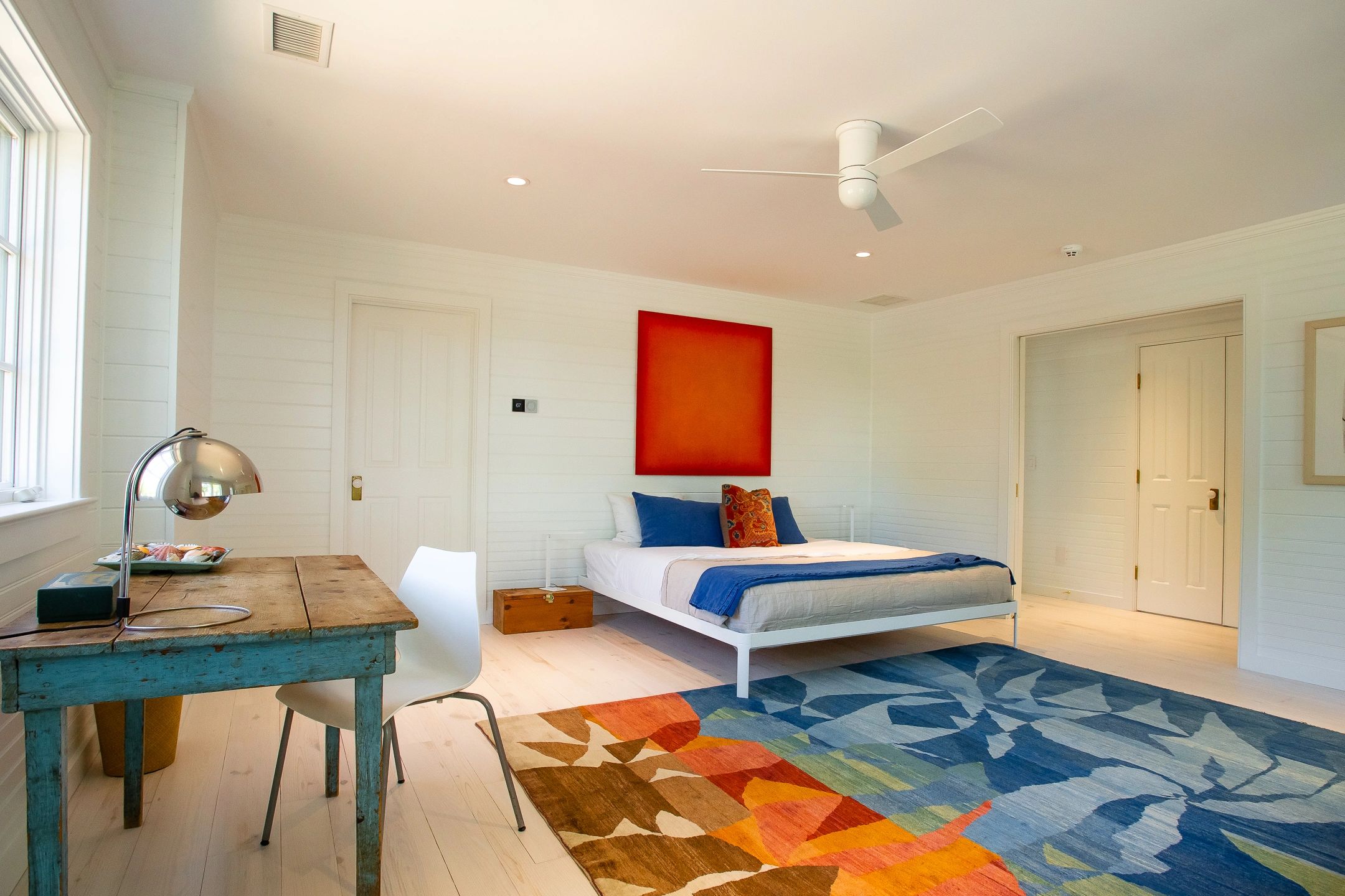 Bright bedroom with colorful rug and simple bed.