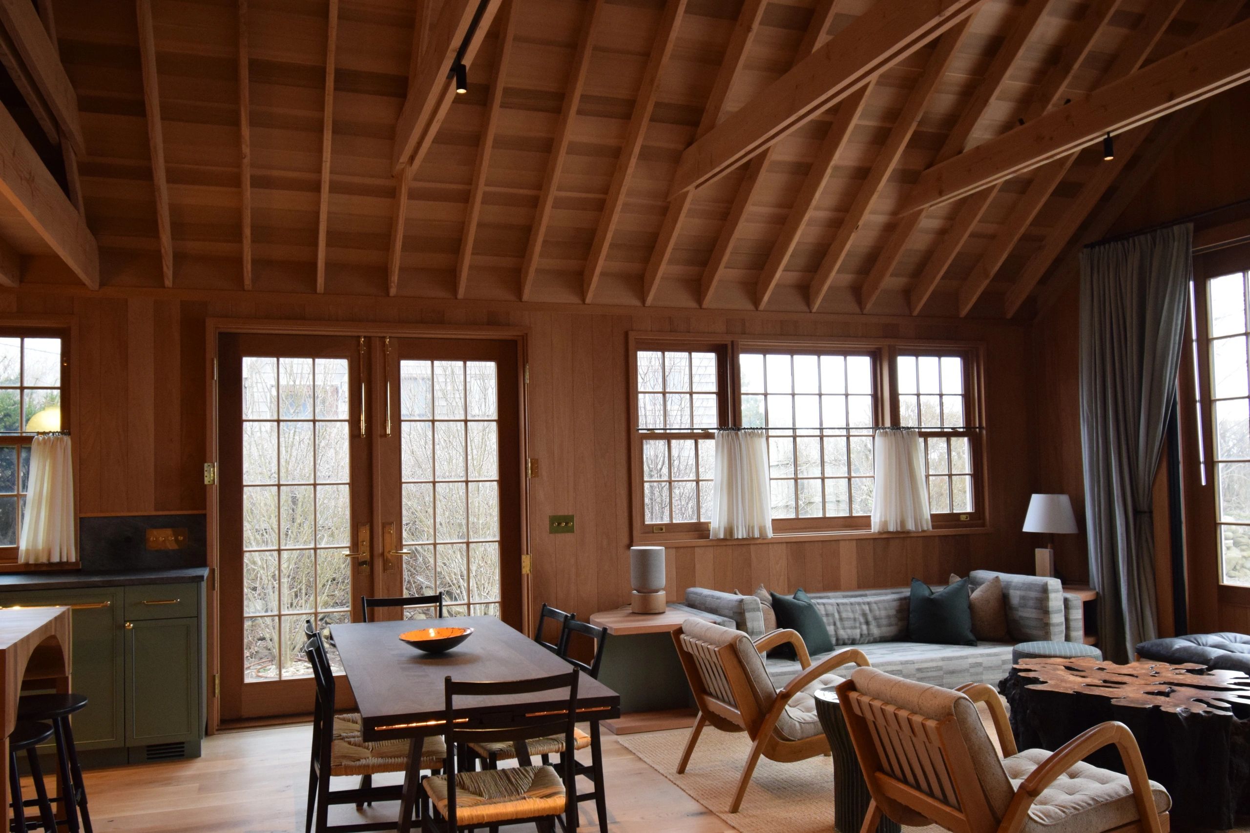 Cozy wooden living and dining area with large windows and comfortable seating.