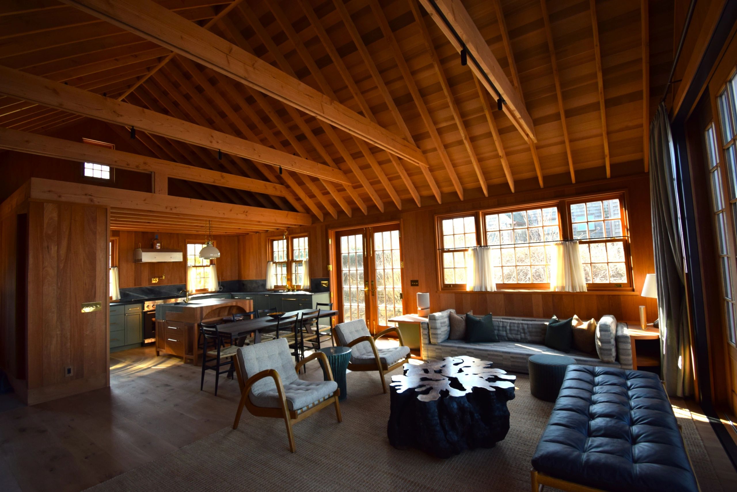 Cozy cabin interior with wooden beams and ample natural light.