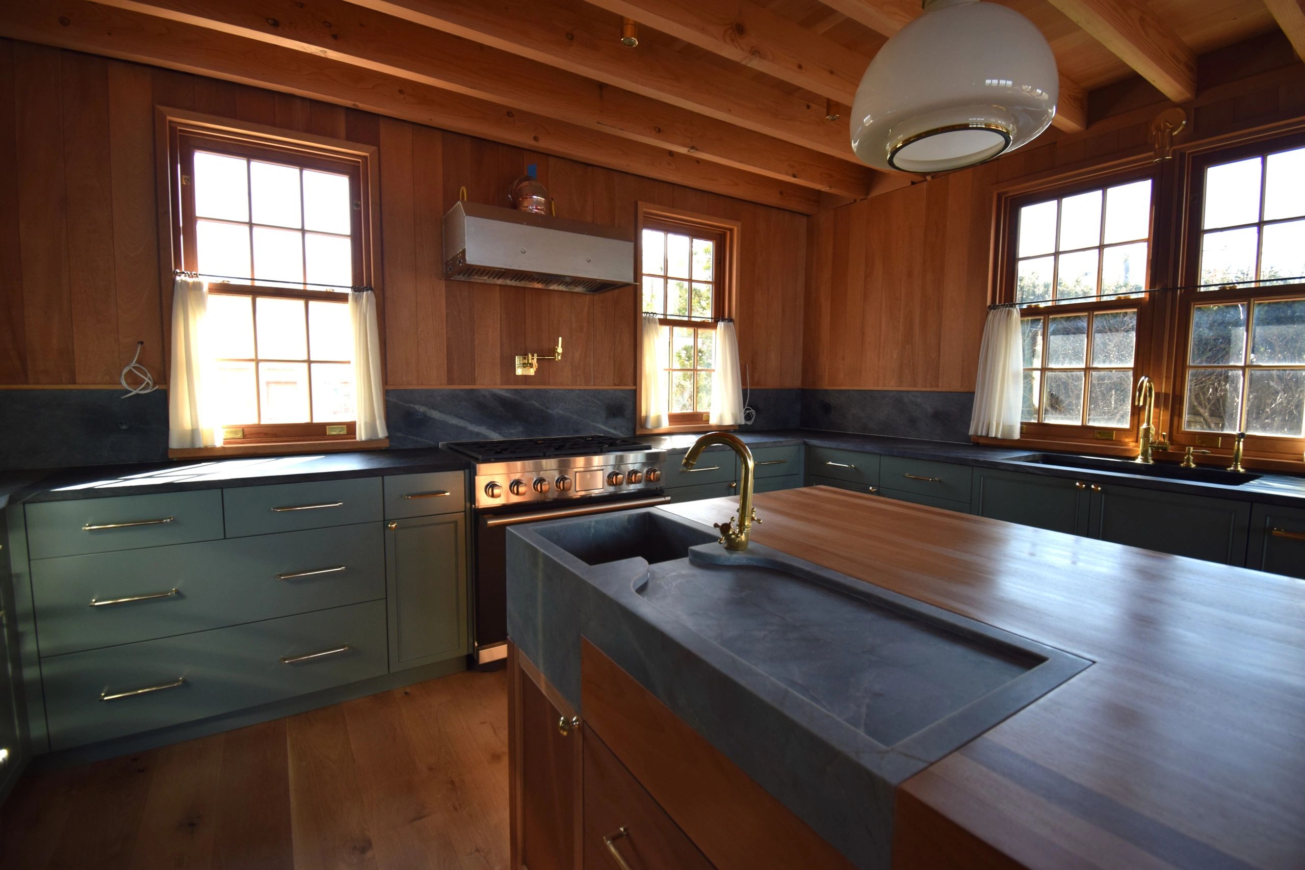 Rustic kitchen with wood walls and brass fixtures.