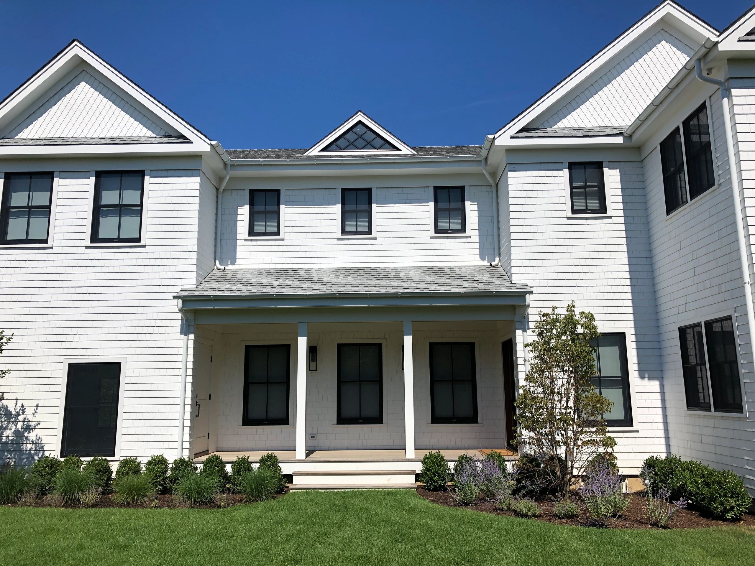 Modern white house with black windows under a clear blue sky.