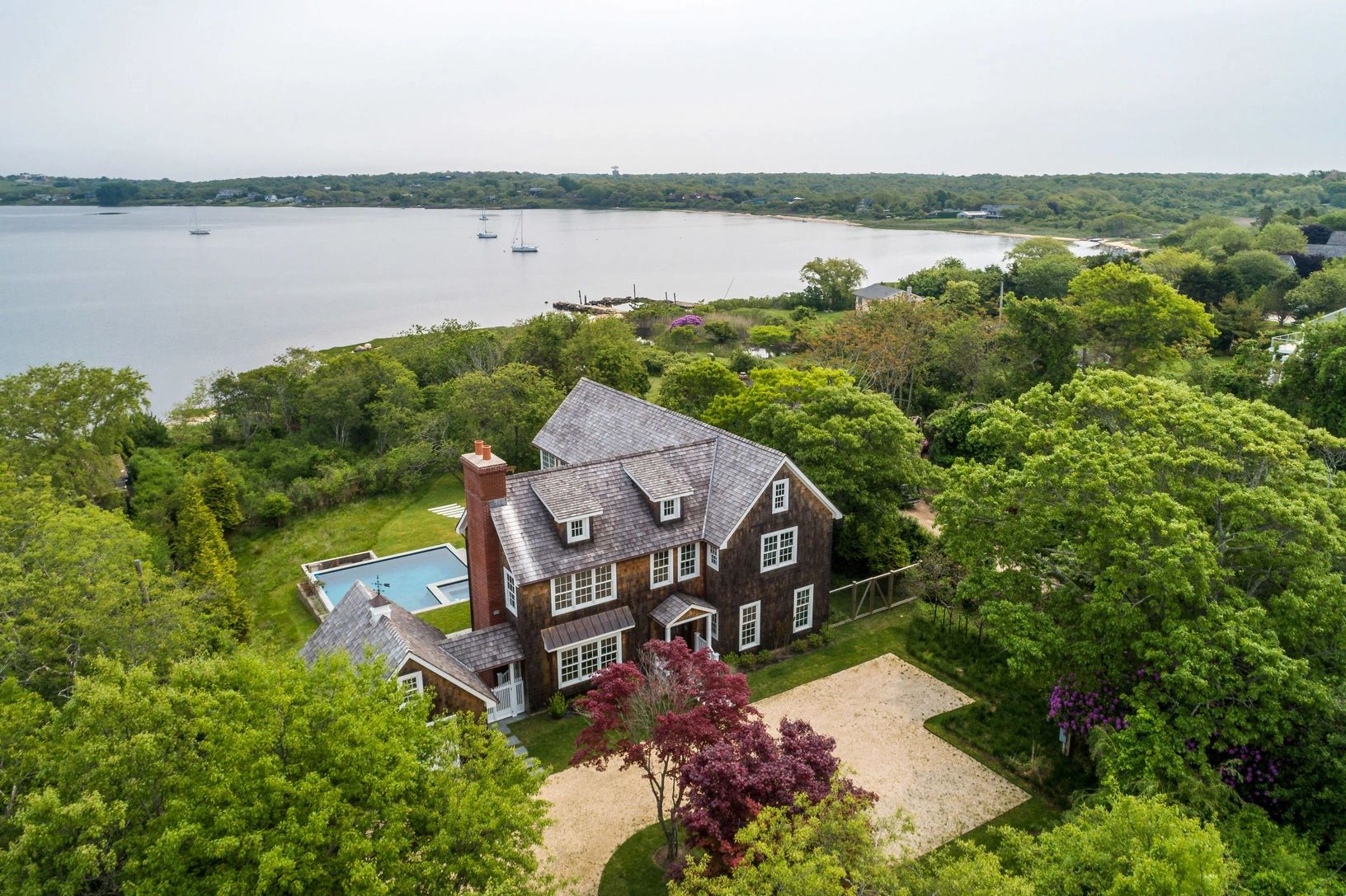A lakeside house surrounded by greenery and trees.
