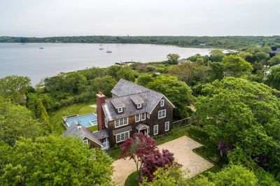 Large house surrounded by greenery near a body of water.