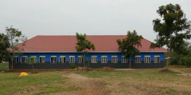 A blue and black building with a red roof surrounded by trees.
