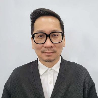 Man wearing glasses and a black textured jacket over a white shirt.