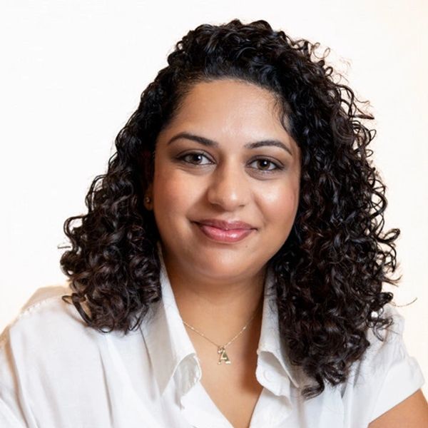 Smiling woman with curly hair and white shirt.