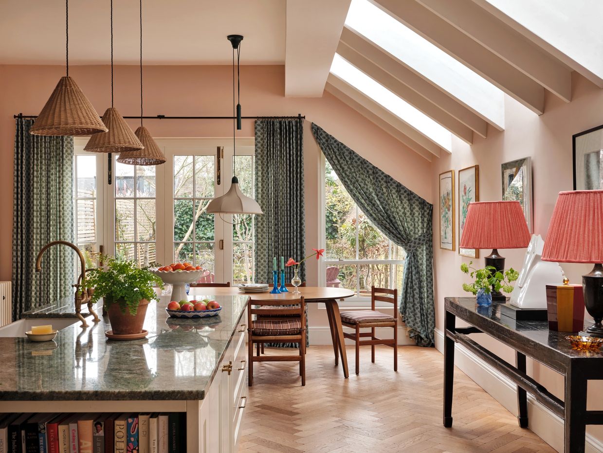Cozy kitchen with pink walls, wicker pendant lights, and natural light from skylights.