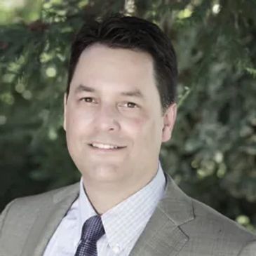 Man in suit smiling outdoors.