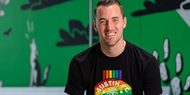 Brad Stuver smiling and wearing a rainbow Austin FC shirt in allyship to the LQBTQIA+ community