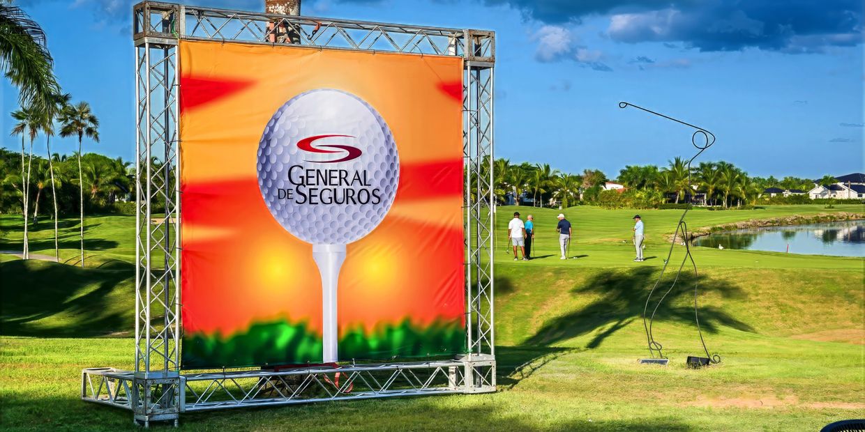 Golf course with General de Seguros advertisement and golfers.