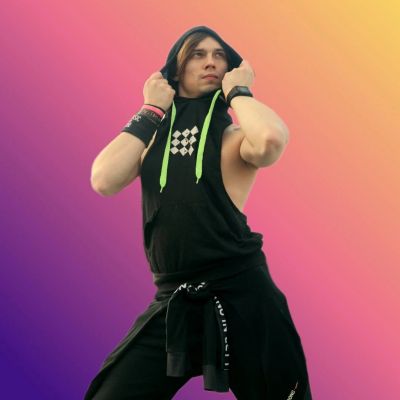 Man in black sleeveless hoodie posing confidently.