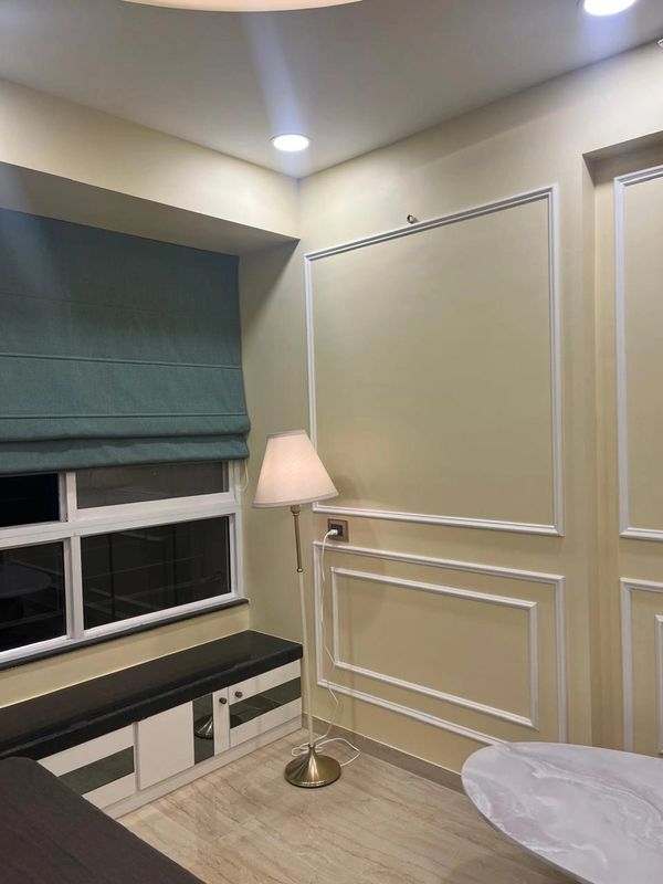 Cozy corner with a floor lamp, window seat, and blue Roman shades in a softly lit room.