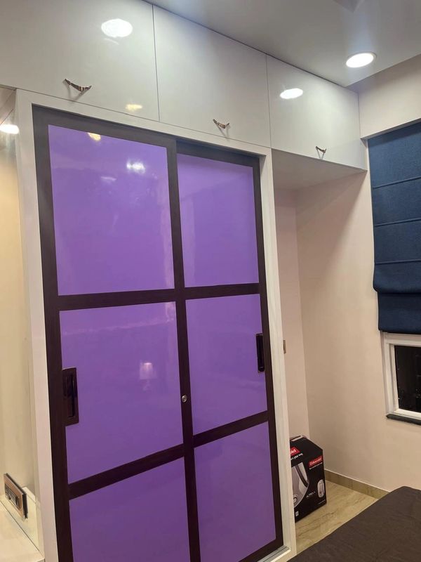 Modern closet with purple sliding doors and white overhead cabinets.