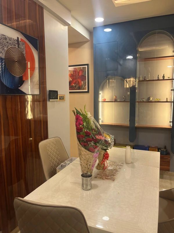 Modern dining room with a white table, beige chairs, and flower bouquets.