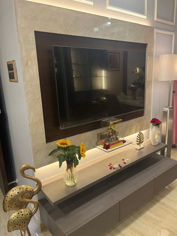 Modern TV unit with decorative flowers, statues, and warm lighting.