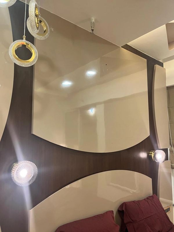 Modern bedroom ceiling with circular pendant lights and maroon pillows below.