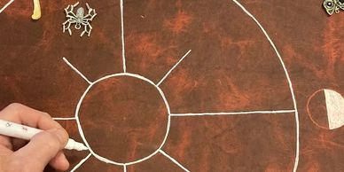Hand drawing a circular segmented chart on a brown surface.