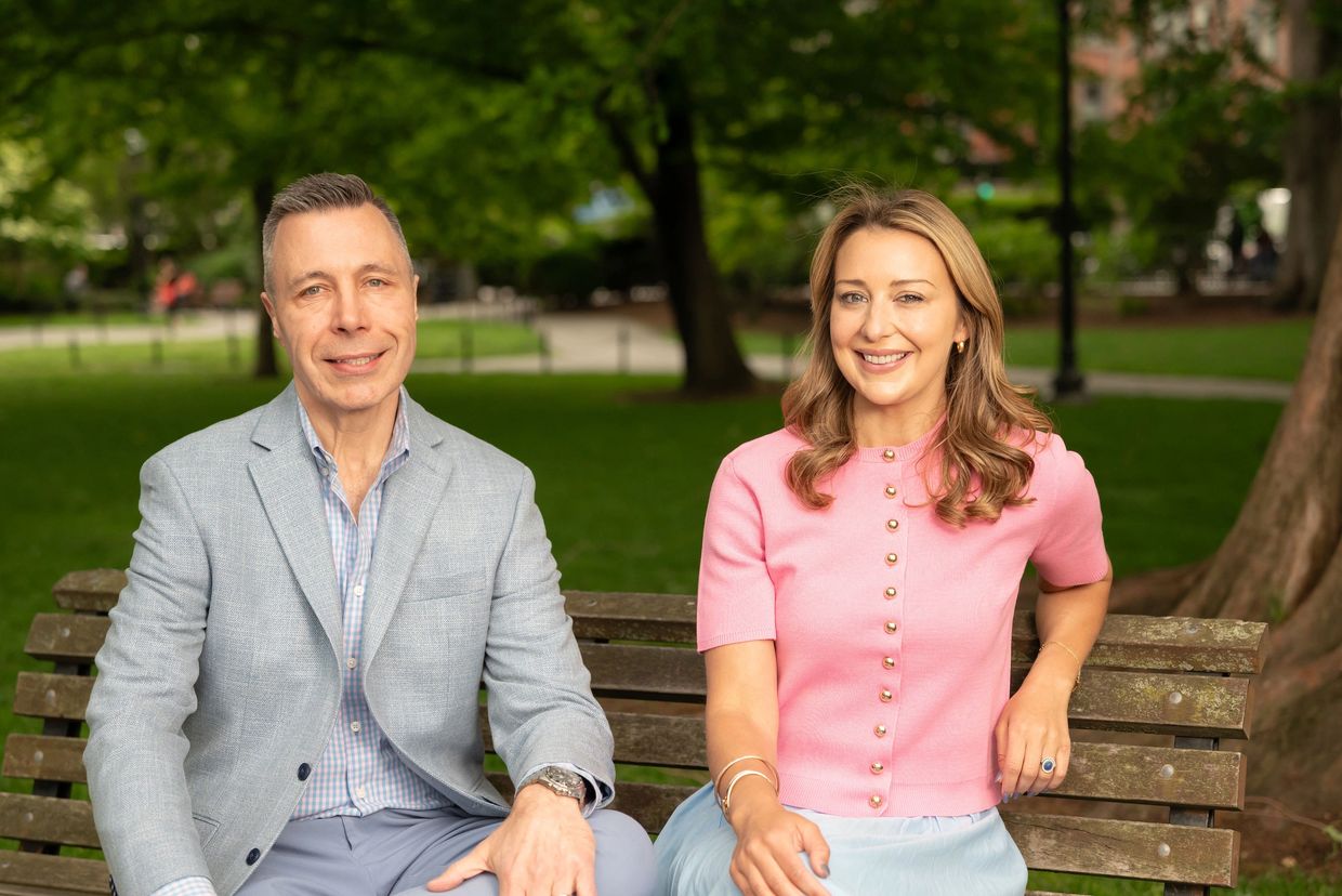 Two people sitting on a park bench smiling.