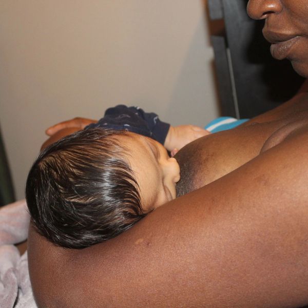 A mother breastfeeding her newborn baby in a close embrace.