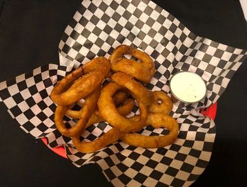 Onion rings in a basket with ranch dipping sauce