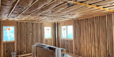 Interior room under construction with exposed insulation and framing.
