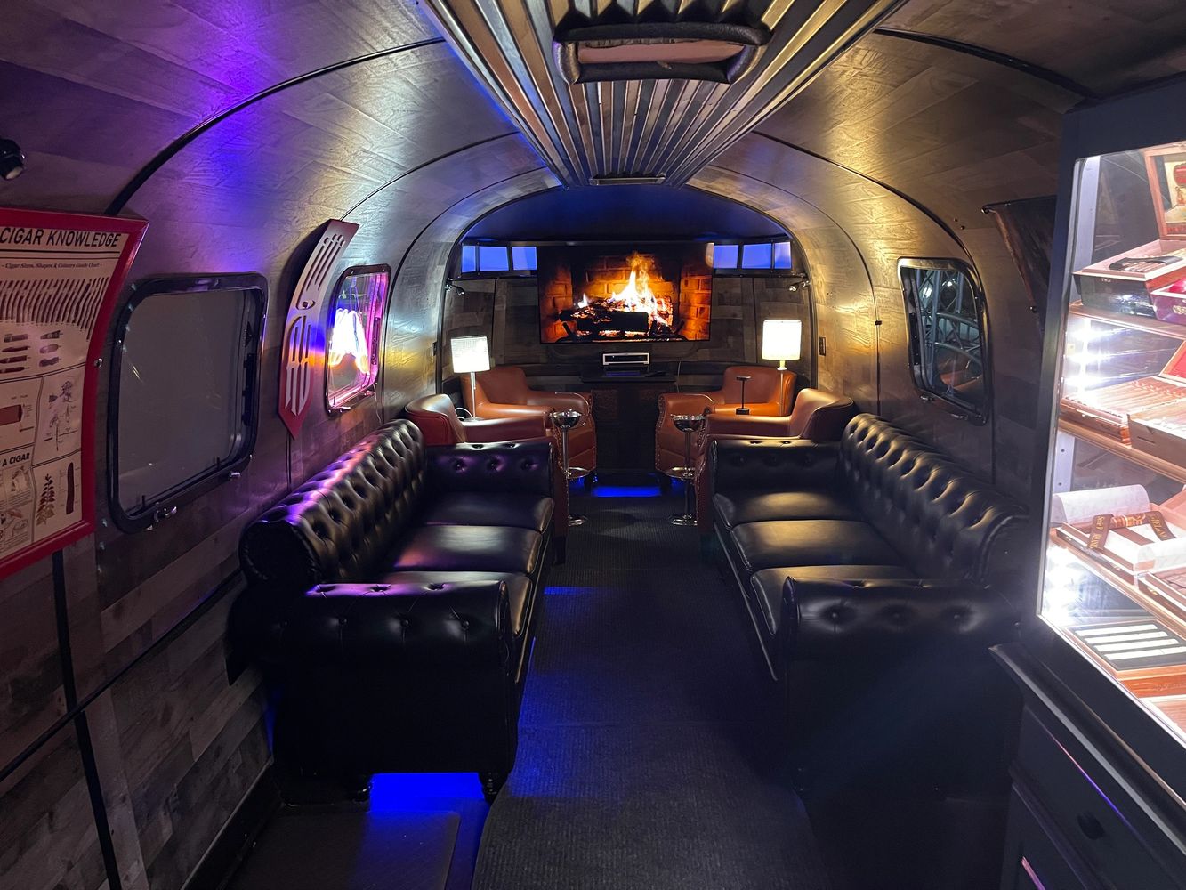 Cozy lounge with leather sofas and a TV showing a fireplace.