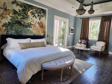 Elegant bedroom with a large bed, bench, and seating area by windows.