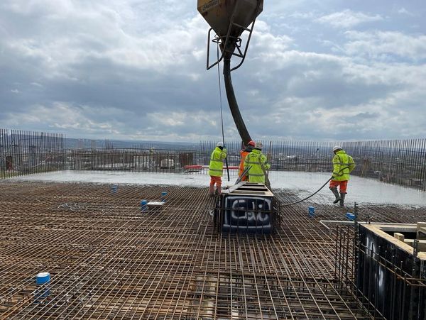 A construction worker pouring wet concrete at a construction site 