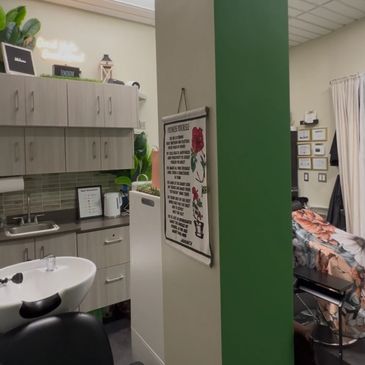A cozy salon corner with a sink, chairs, and a floral-covered treatment bed.