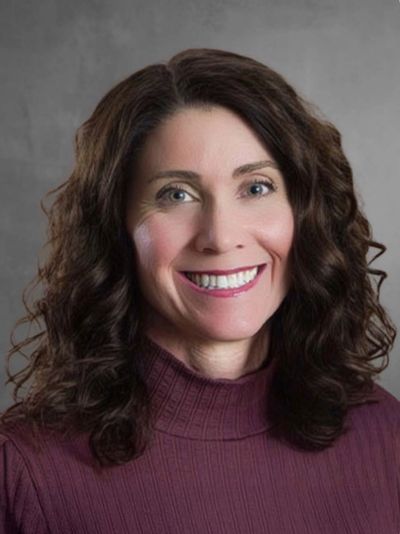 Woman with dark curly hair smiling.