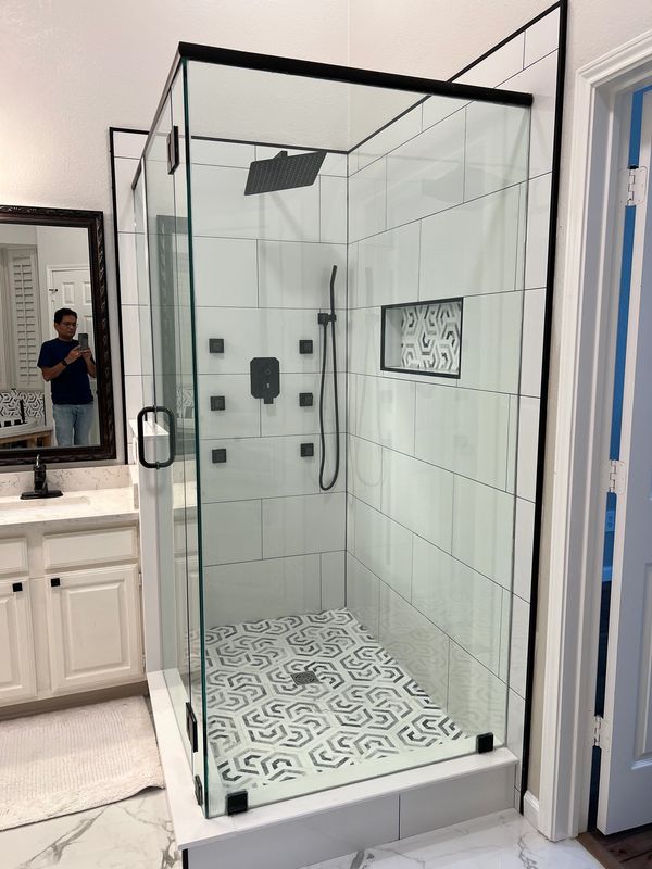 Modern bathroom shower with glass enclosure and patterned tile floor.