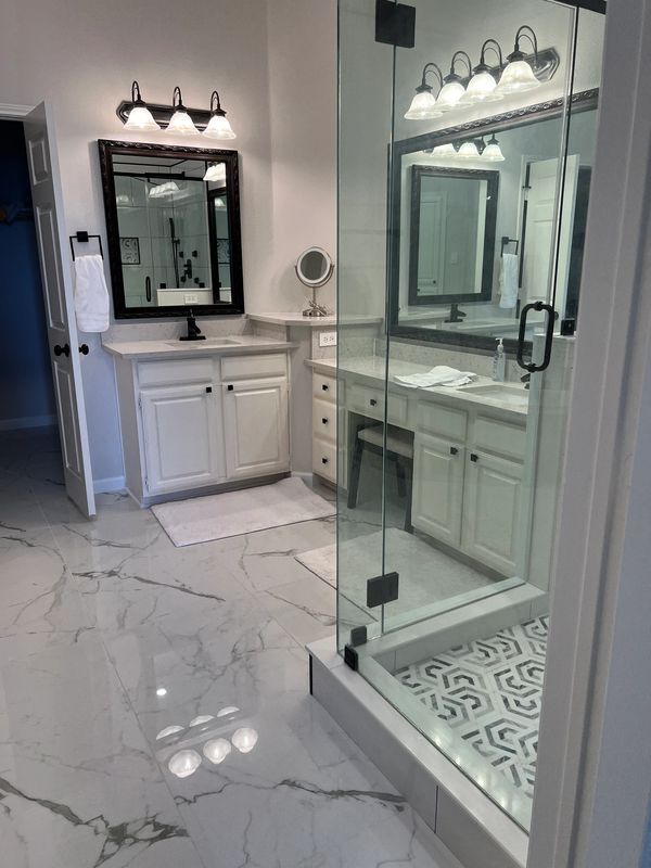 Modern bathroom with marble floors and glass shower enclosure.
