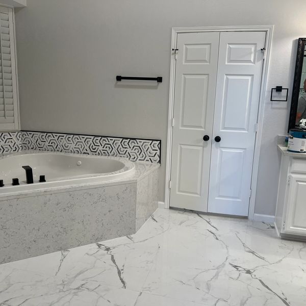 Modern bathroom with a large bathtub and white marble flooring.