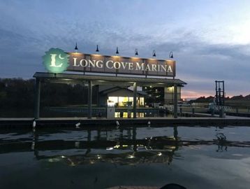 Evening view of Long Cove Marina with illuminated sign and calm water reflections.