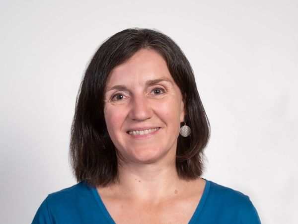 Frau mit blauem T-Shirt lächelt in die Kamera