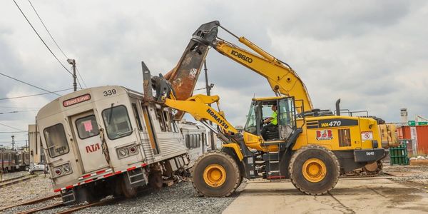 Construction machinery lifts a derailed train car off the tracks.