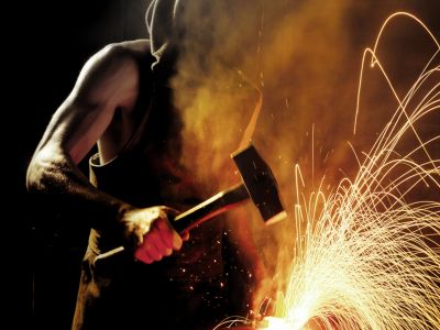A blacksmith striking metal, sparks flying.