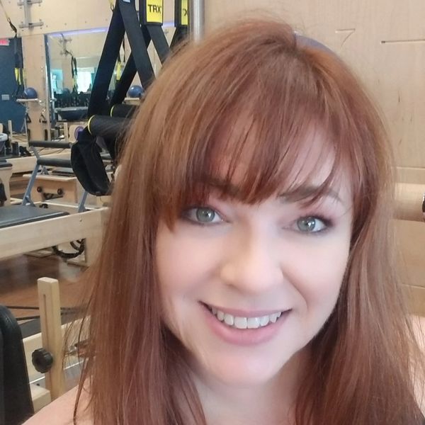Smiling woman with red hair in a gym setting.