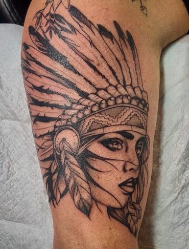 Tattoo of a woman wearing a Native American headdress with intricate feather details.