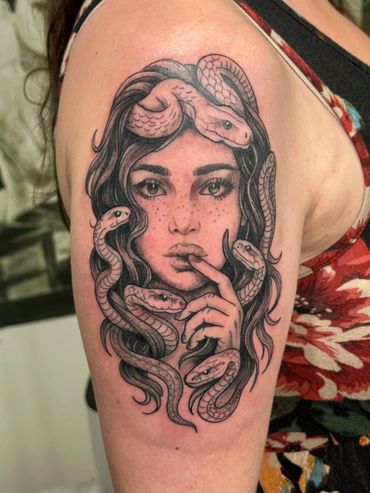 Tattoo of a woman with snakes entwined in her hair on an arm.