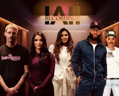 Group of five diverse young adults posing in a recording studio.